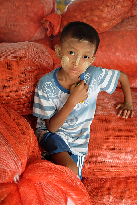 Local Child sitting on Orange Sacks